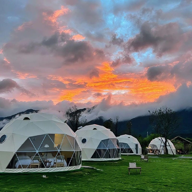 Interior de glamping con cama y vistas al paisaje